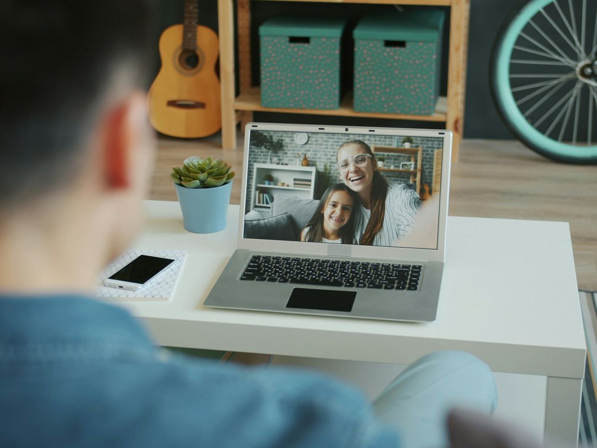Father on a video call with mother and daughter on a laptop